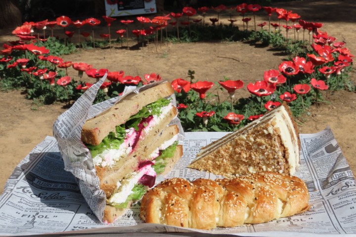 כריך, מאפה גבינה ועוגת גזר גבינה לצד מיצב כלניות אדומות