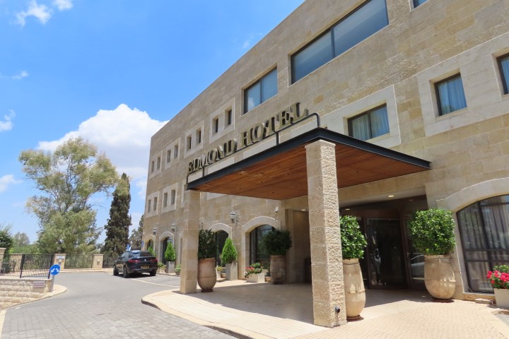 חזית המלון מוקפת ברושים וצמחייה בראש פינה